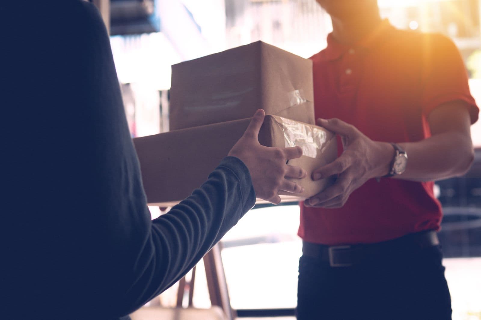 A Stallionex courier handing a wrapped parcel to a customer